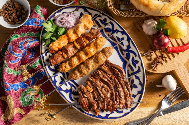 Półmisek kebabów. Uch-panzha z jagnięciny, kebab kebab z kurczaka z jagnięciną, szaszłyk z kurczaka i szaszłyki jagnięce na talerzu z tradycyjnym ornamentem Uzbekistanu.