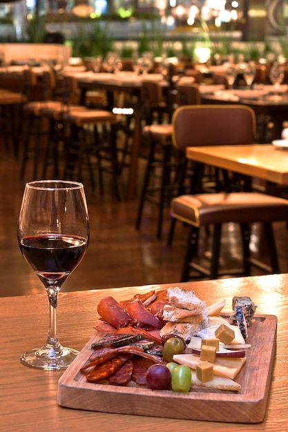 Półmisek serów i wędlin w towarzystwie lampki czerwonego wina na drewnianym stole w restauracji