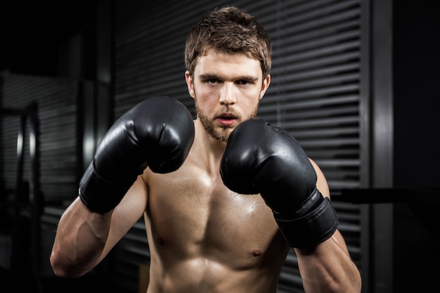 Półnagi mężczyzna z rękawicami bokserskimi na siłowni crossfit