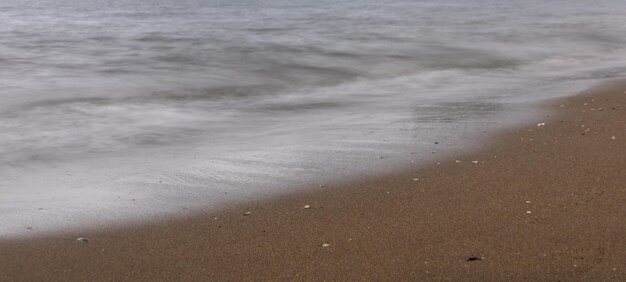 PÓŁNOCNA PLAŻA Z FALAMI I SKAŁAMI POD ZACHEMNYM NIEBEM WIOSNĄ