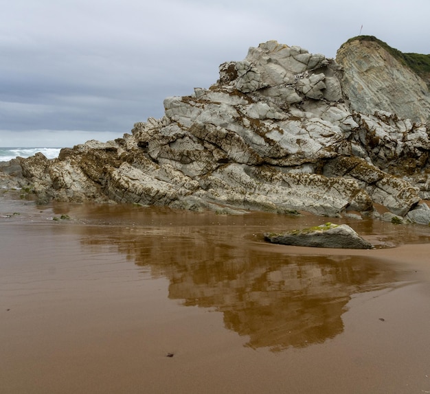 PÓŁNOCNA PLAŻA Z FALAMI I SKAŁAMI POD ZACHEMNYM NIEBEM WIOSNĄ