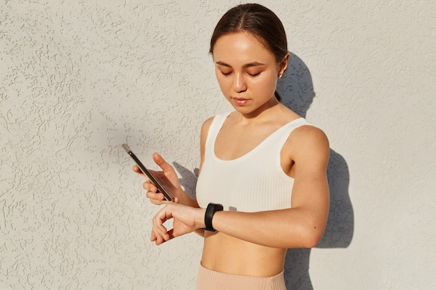 Zdjęcie połowa długości portret wysportowanej kobiety łączącej smartfon z zakrętem fitness przed treningiem na świeżym powietrzu lub bieganiem