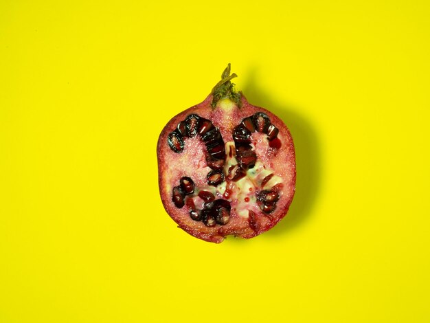 Połowa granatu na żółtym sok owocowy na żółtem tle Naciśnięty granat żywność wegańska żywność surowa dieta sok składnik