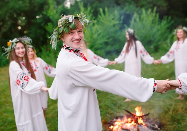 Połowa lata. Młodzi ludzie w słowiańskich ubraniach krążą wokół ogniska w środku lata. .