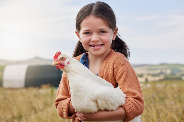Pomagam opiekować się zwierzętami w naszym gospodarstwie. Ujęcie uroczej dziewczynki trzymającej kurczaka na farmie.