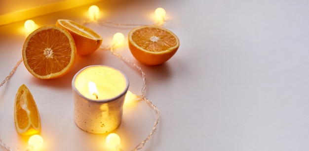 Zdjęcie pomarańcze, świeca i boże narodzenie światła na jasnym tle. skopiuj miejsce