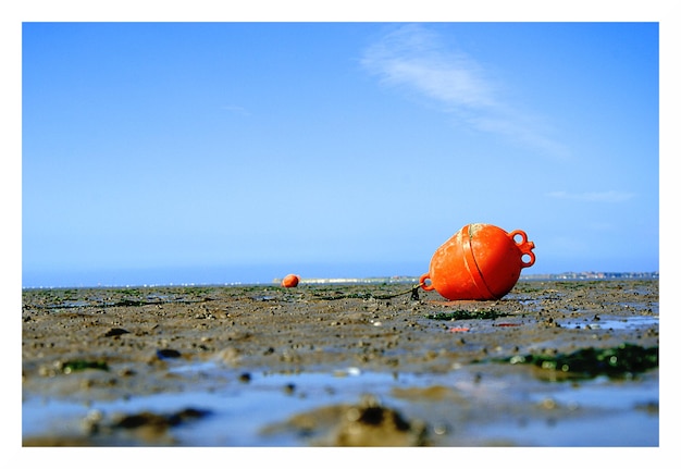 Pomarańczowa bója na plaży na tle nieba