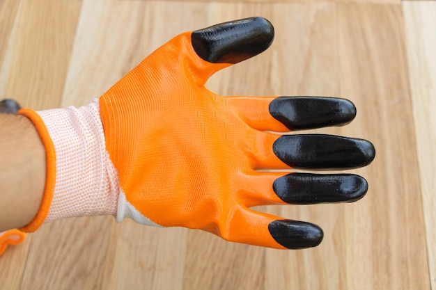 Zdjęcie pomarańczowa rękawica budowlana ubrana w drewniane tło dłoni