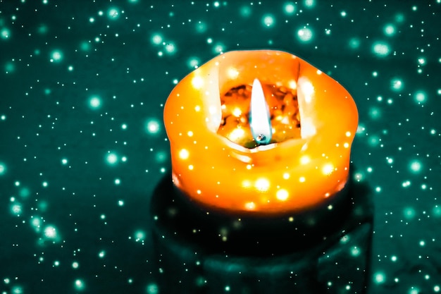 Zdjęcie pomarańczowa świeca wakacyjna na zielonym tle musującego śniegu luksusowy projekt marki na halloween, sylwestra i boże narodzenie