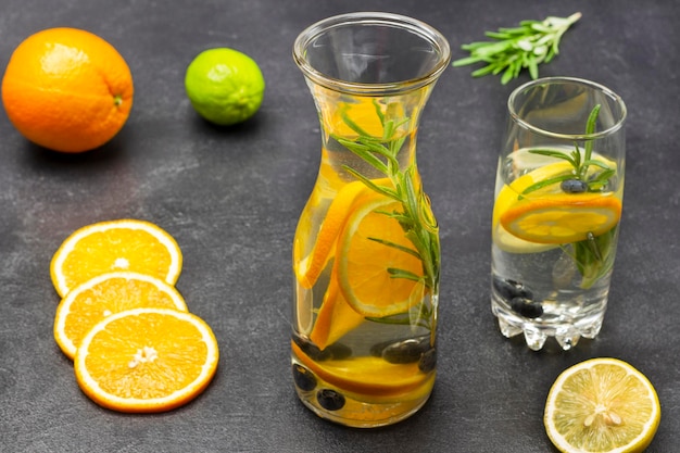 Pomarańczowe jagody i woda z rozmarynem w szklance i butelce