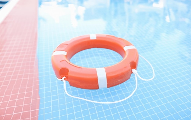 Pomarańczowe plastikowe koło ratunkowe unoszące się w basenie z bliska