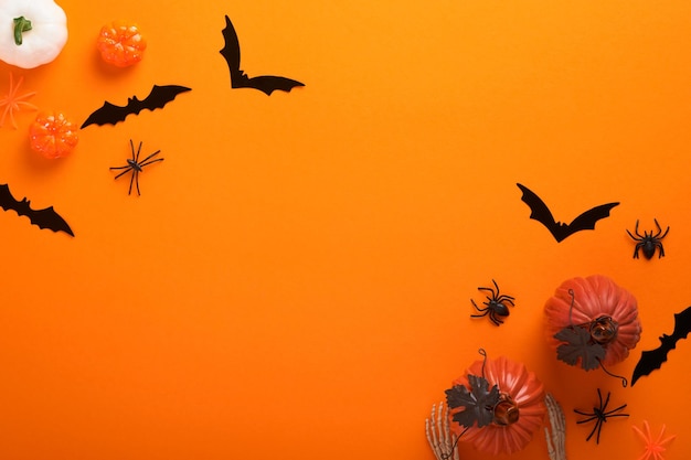 Pomarańczowe tło Halloween Stado czarnych nietoperzy pająk dynia szkielet i liście na Halloween Czarne papierowe sylwetki nietoperzy na pomarańczowym tle Jesienna dekoracja Koncepcja Halloween Widok z góry