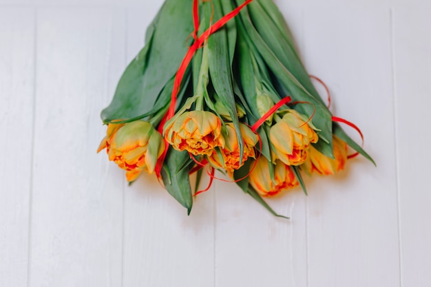 Pomarańczowi tulipany na białym drewnianym tle