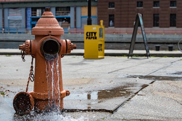 Pomarańczowy hydrant uliczny rozprowadzający wodę po ulicy