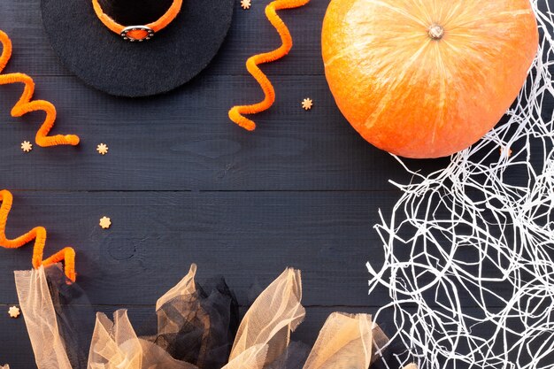 Zdjęcie pomarańczowy i czarny flatlay na halloween. dynia, tiul, pajęczyna na czarnym tle drewna. skopiuj miejsce