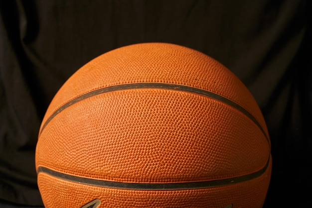Pomarańczowy klasyczny szczegół koszykówki przed czarnym tłem