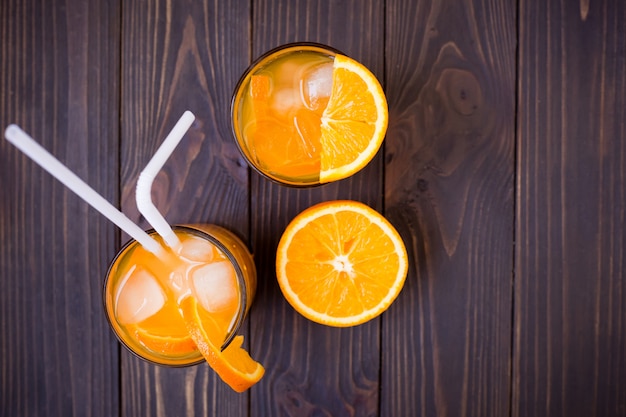 Pomarańczowy napój i pokrojona pomarańcze na brown tle