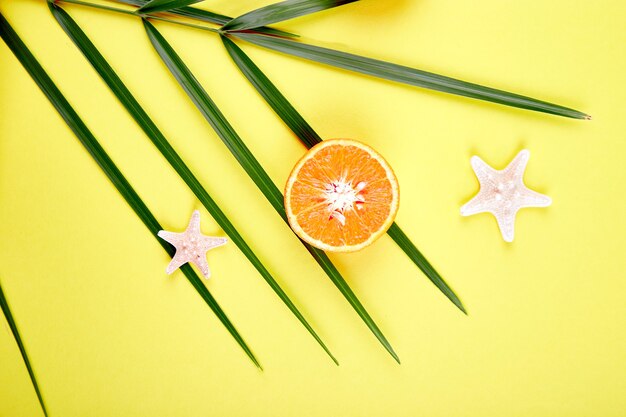 Zdjęcie pomarańczowy owoc, rozgwiazda i liście palmowe