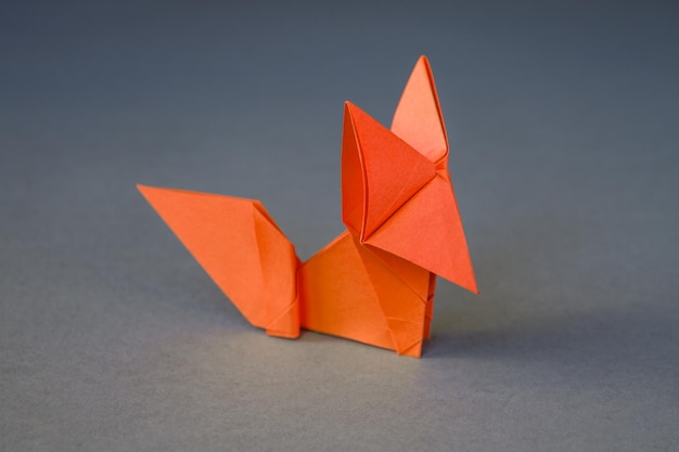 Pomarańczowy papierowy lis origami na białym tle na szarym tle
