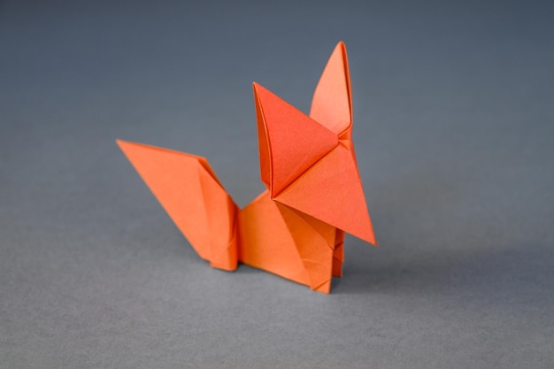 Pomarańczowy papierowy lis origami na białym tle na szarym tle