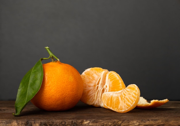 Pomarańczowy tangerine z zielonym liściem Kawałek podzielony na pół i obrane Szare tło
