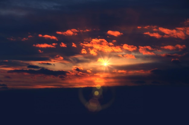 pomarańczowy zachód słońca na nocnym błękitnym niebie dramatyczne chmury i rozbłyski słońca, pejzaż morski natury