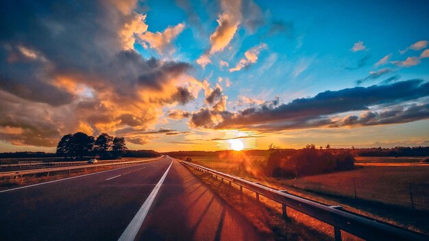 Zdjęcie pomarańczowy zachód słońca z chmurami widok z autostrady