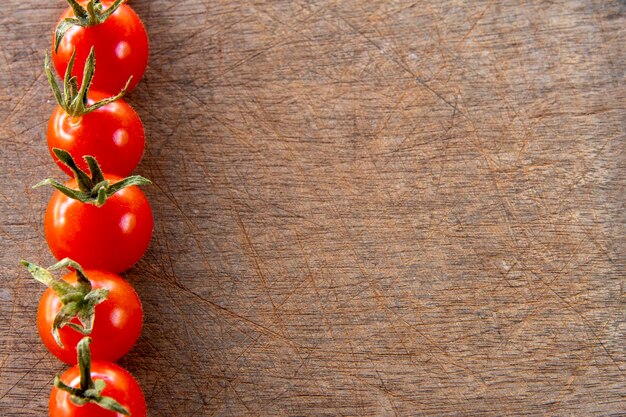 Pomidor czereśniowy tworzący ramkę boczną na porysowanym drewnianym tle