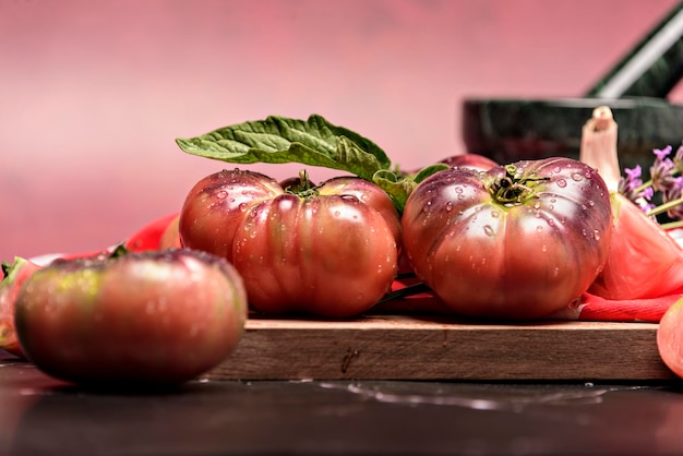 Pomidor tygrysi na desce do krojenia z liśćmi bazylii na drewnianym tle Świeży pomidor zmyty do gotowania Pomidor z kroplami wody