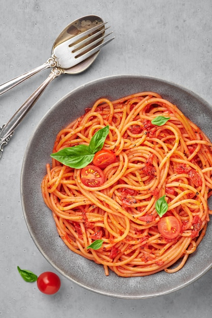 Zdjęcie pomidorowy spaghetti w popielatym pucharze na betonowej powierzchni. makaron w sosie pomidorowym to klasyczne danie kuchni włoskiej. włoskie jedzenie