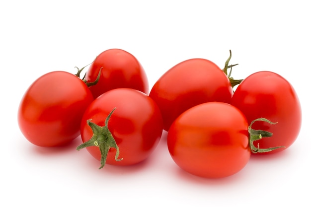 Pomidory koktajlowe. Trzy pomidory czereśniowe na białej powierzchni.
