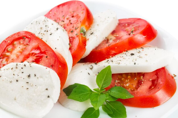 Pomidory mozzarella i liście bazylii na białym tle