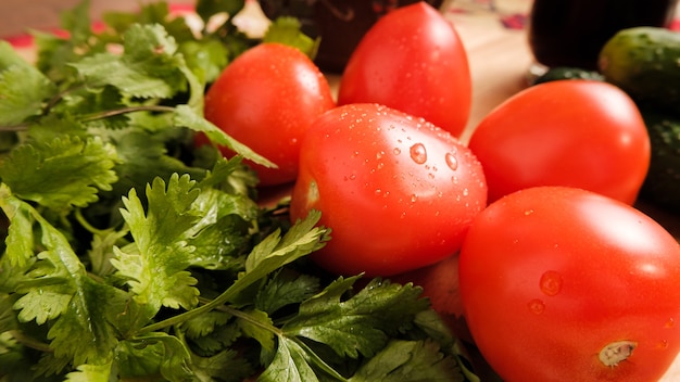 Pomidory, ogórki i zioła na desce do krojenia.