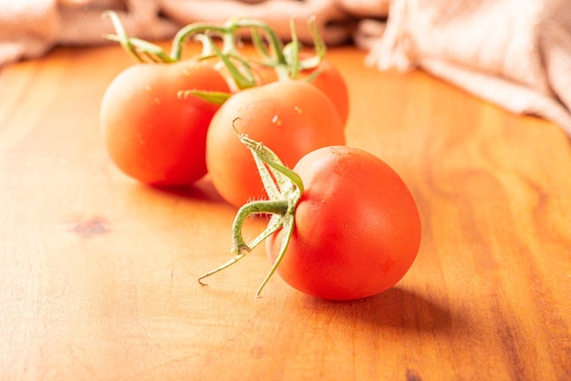 Pomidory piękne szczegóły świeżych czerwonych pomidorów na gałęziach nad rustykalnym drewnem selektywnym