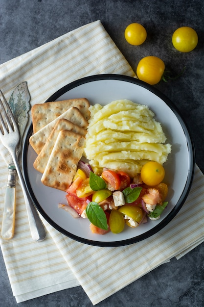Pomidory świeża sałatka i mushed ziemniaki w talerzu. Zdrowe, letnie jedzenie.