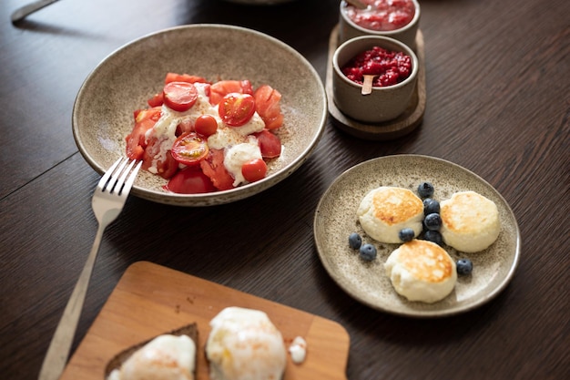 Pomidory z naleśnikami z serem Burrata i innymi potrawami podawane w pięknych talerzach na stole koncentrują się na pomidorach