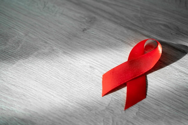 Zdjęcie pomoc czerwoną wstążką na szarym tle marmuru na białym tle. symbolizujący dzień aids i hiv. koncepcja kontroli hiv.