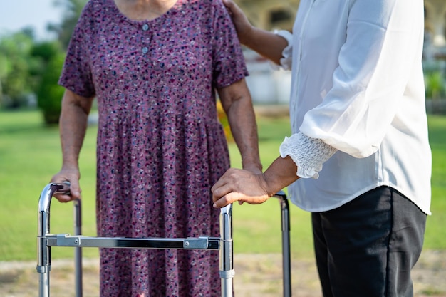 Zdjęcie pomoc i opieka azjatycka starsza lub starsza starsza kobieta używa chodzika z silnym zdrowiem podczas spaceru po parku w szczęśliwych, świeżych wakacjach
