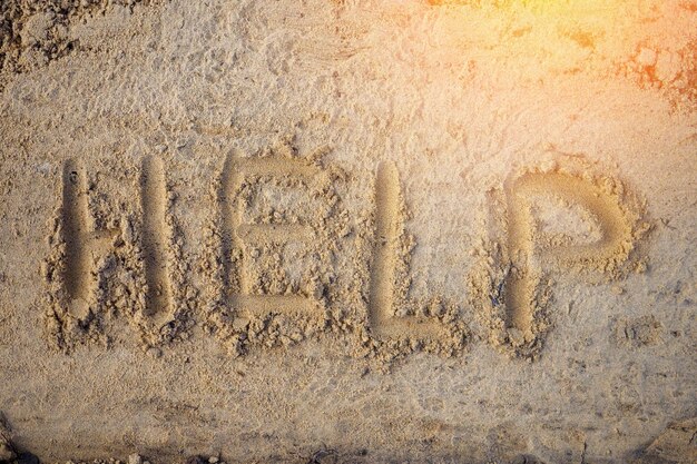 Pomoc Napis literami na piasku Widok z góry Apel o pomoc