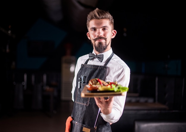 Pomocny Kelner Z Przyjemnością Podaje W Restauracji Apetyczne Danie.