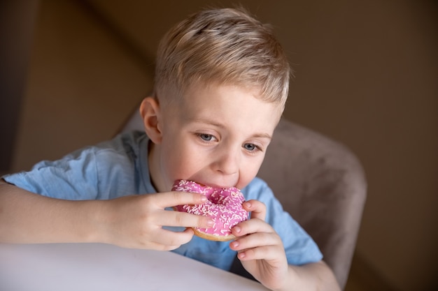 Pomysł To Bezużyteczne Jedzenie Mały Chłopiec O Blond Włosach Je W Domu Różowego Pączka