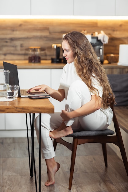 Pomyślna Dziewczyna śmia Się I Pracuje W Domu. Piękna Stylowa Kobieta Uśmiechnięta I Relaksuje W Domu. Bizneswoman Przedsiębiorca Pracuje Na Laptopie Z Domowego Biura