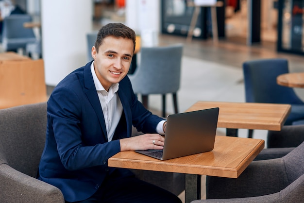 Pomyślny Młody Biznesmen Pracuje Na Laptopie W Sklep Z Kawą