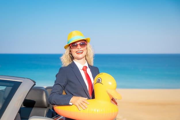 Pomyślny młody bizneswoman na plaży. Kobieta stojąca w pobliżu klasycznego samochodu kabriolet.