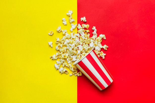 Popcorn w czerwono-białym kartonie na czerwonym i żółtym