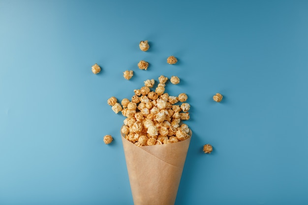 Popcorn w glazurze karmelowej w papierowej kopercie na niebiesko.