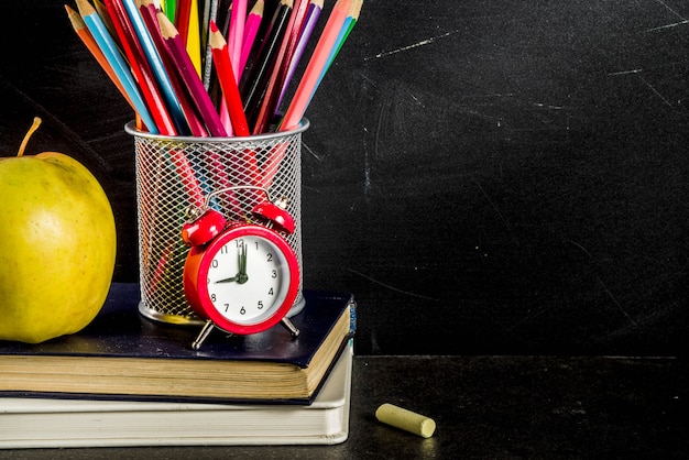 Popiera szkoły pojęcie z książka budzika koloru ołówków chalkboard tłem