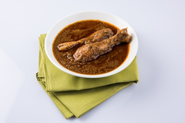 Popularne czerwonawe curry z kurczaka lub masala, z wyraźnym kawałkiem nogi, podawane w misce