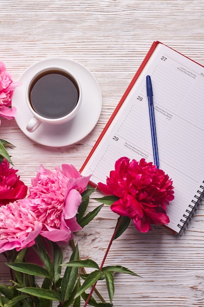 Poranna kawa na śniadanie pusty notatnik ołówek i różowe kwiaty piwonii na białym kamiennym stole t...
