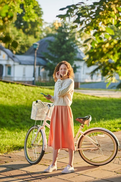 Poranna przejażdżka. Dziewczyna w różowej spódniczce z rowerem w parku
